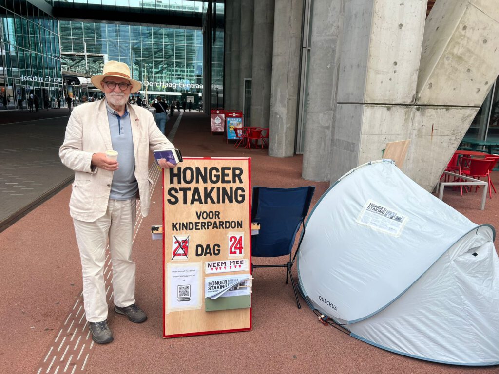 Een strijdbare en trotse EDuard Disch met zijn protestbord met daarop de tekst Hongerstaking voor een een generaal kinderpardon